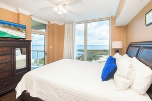 Une chambre dâhĂŽtel avec un lit, une tĂ©lĂ©vision, un ventilateur de plafond et une vue sur lâocĂ©an.