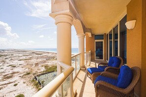 Un balcon doté de meubles en osier et offrant une vue sur la plage.