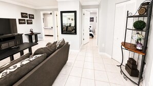 Ein modernes Wohnzimmer mit einer Couch, einem Fernseher und einem Essbereich mit Tisch und Stühlen.