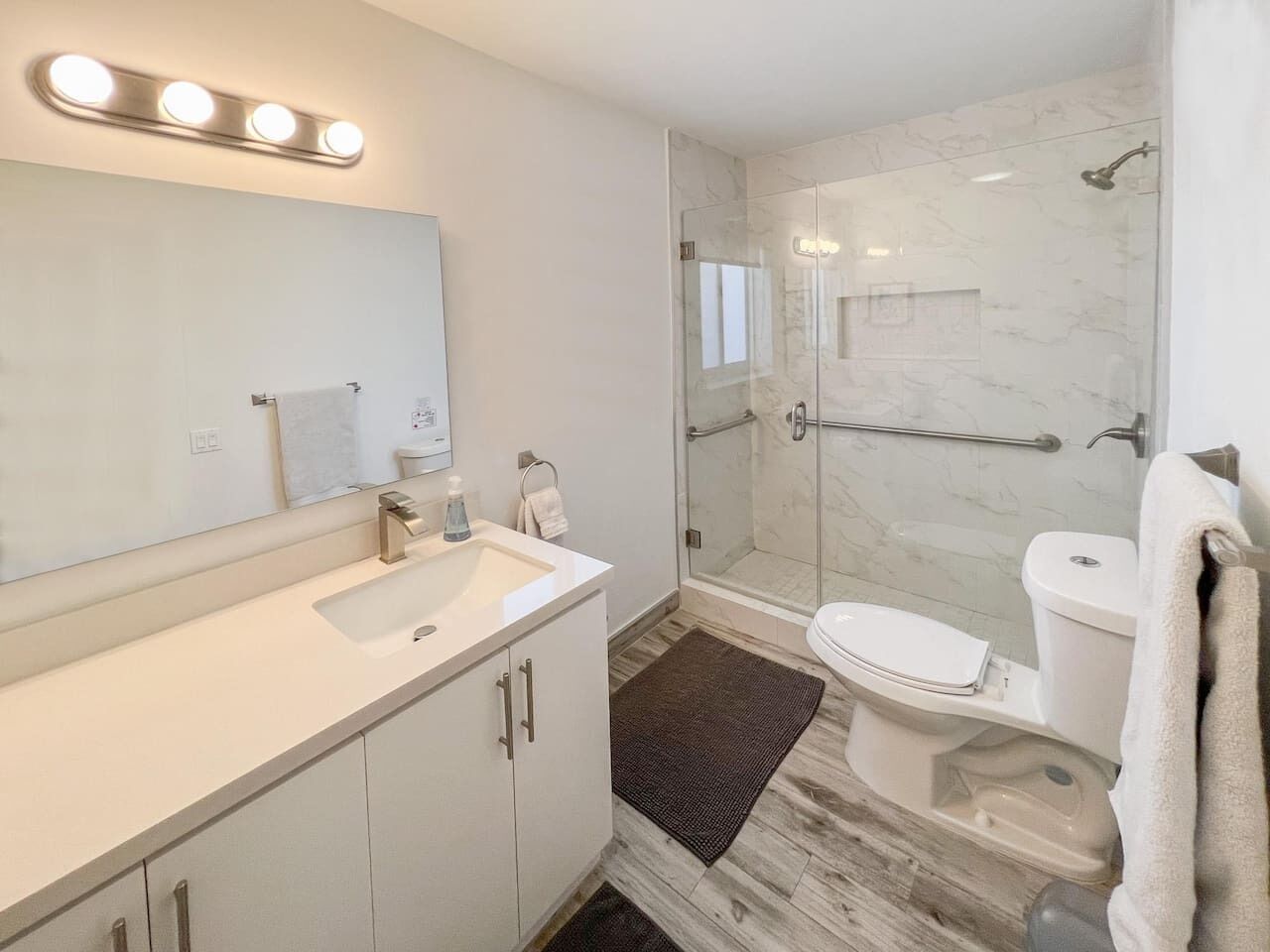 Une salle de bain moderne avec une douche à parois de verre, un lavabo blanc et des toilettes.