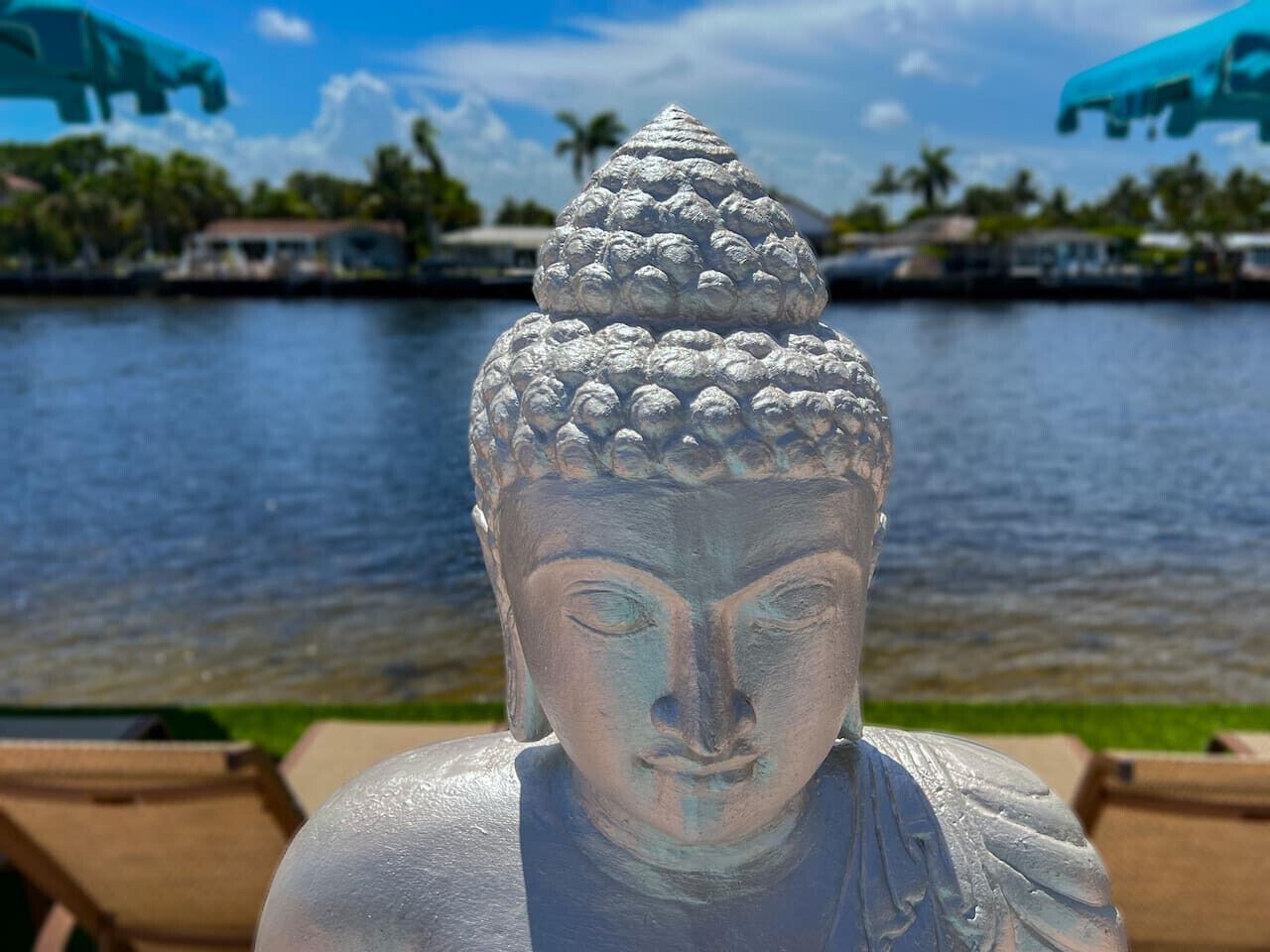 A Buddha statue with a detailed headdress in front of a body of water.