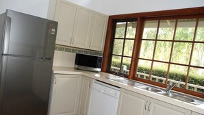 A kitchen with white cabinets, a stainless steel refrigerator, a dishwasher, and a microwave.