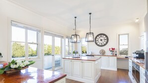A spacious kitchen with wooden flooring, white cabinetry, and large windows offering a view of trees. - Expansive Hamptons home on acreage, with pool, spa, gym, tennis court & views. (Kangaloon)