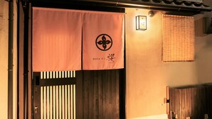 A traditional Japanese entrance with a wooden door and sliding paper doors, a tiled roof, and a lantern on the wall. - Hosta Toji Sakura (Kyoto)