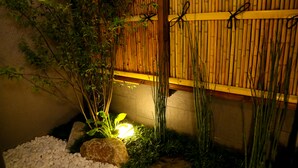 A traditional Japanese garden with a bamboo fence, a stone lantern, and a pebbled ground. - Hosta Toji Sakura (Kyoto)