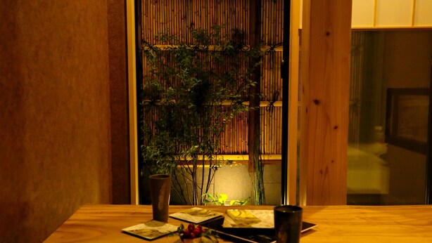 A wooden table with a vase, a plate, and a cup. - Hosta Toji Sakura (Kyoto)