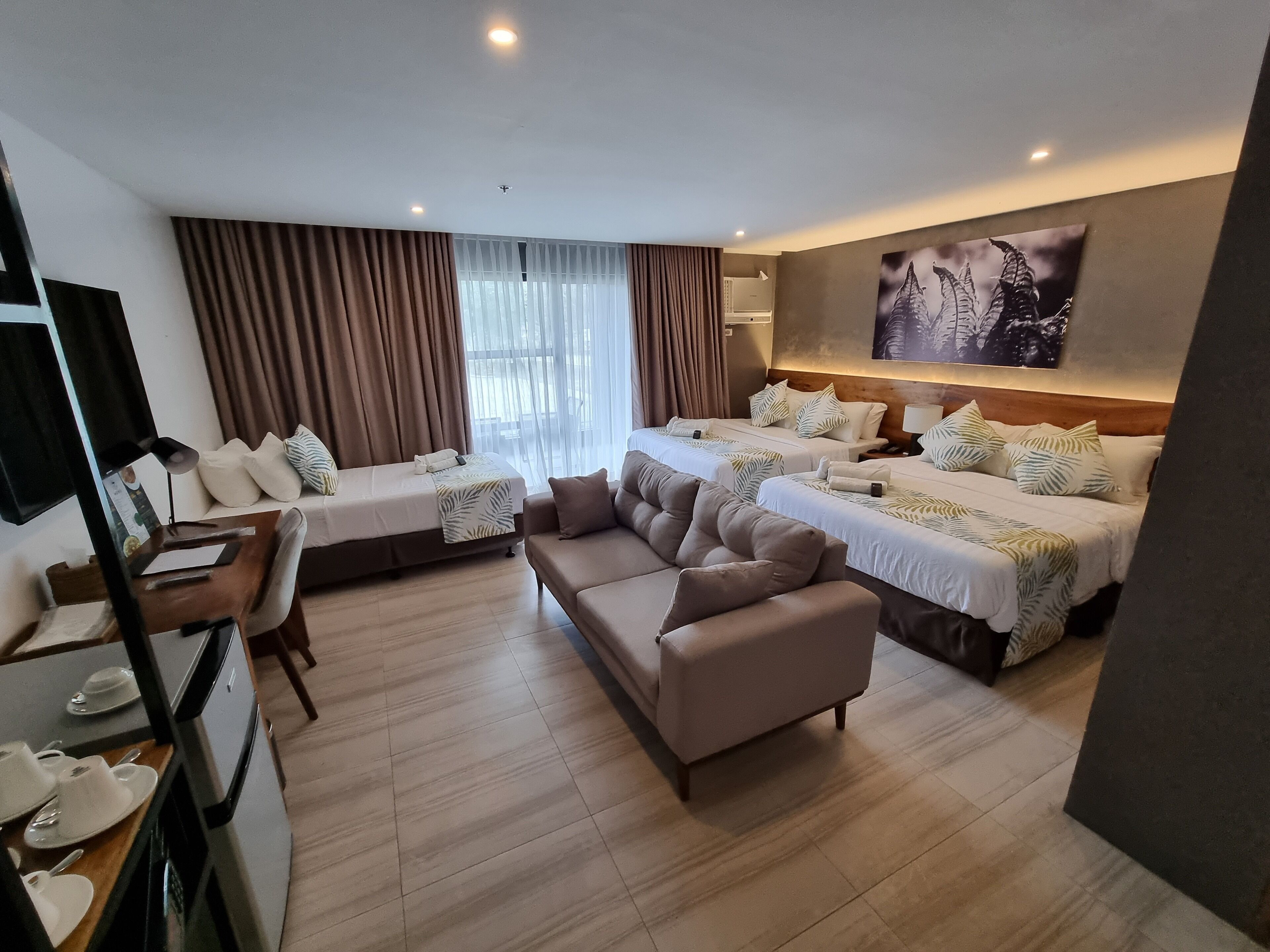 A hotel room with two beds, a sofa, a desk, and a dining area.