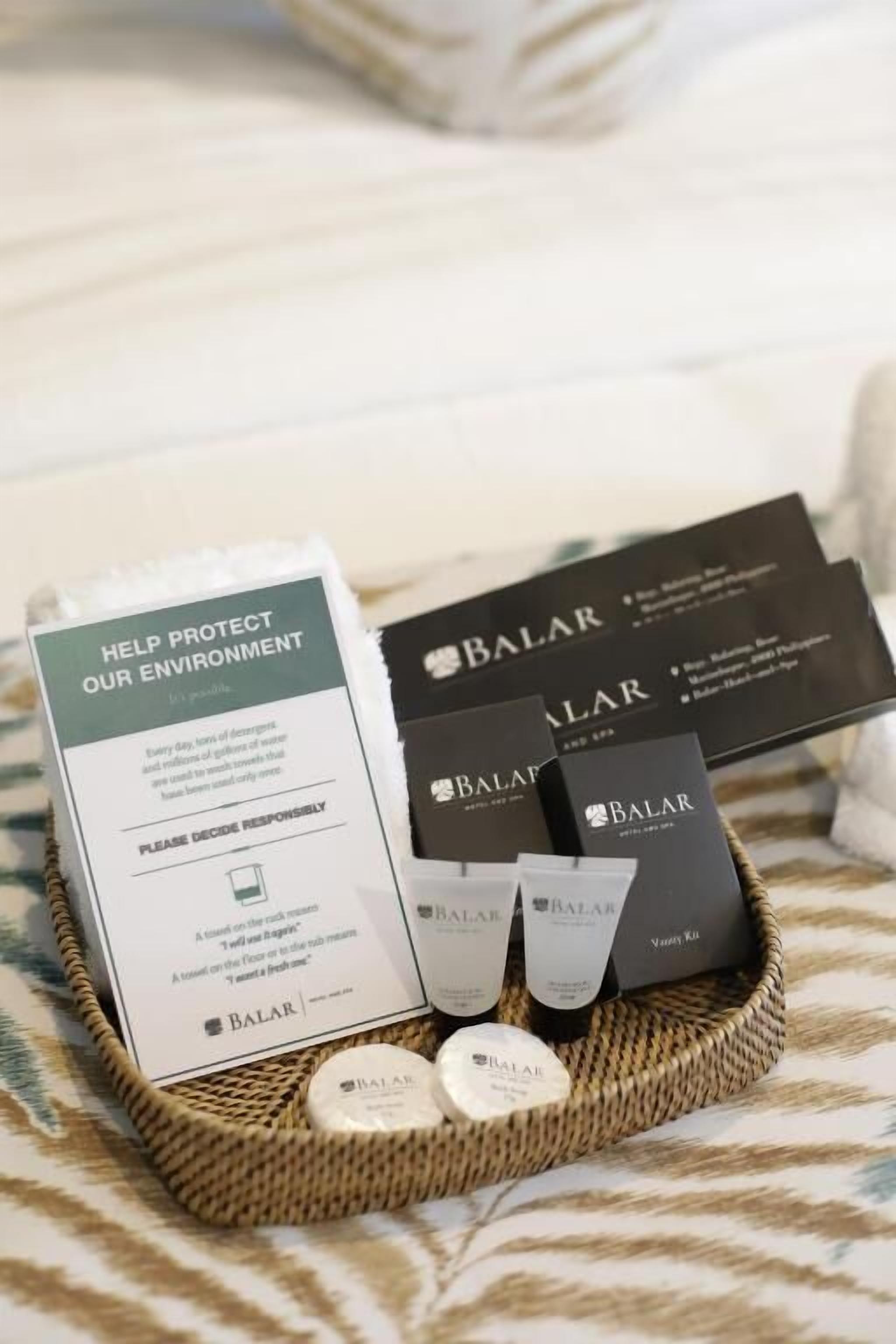 Un panier en osier contenant des produits de soins pour la peau de la marque Balar et une boîte avec un message sur la protection de l’environnement.
