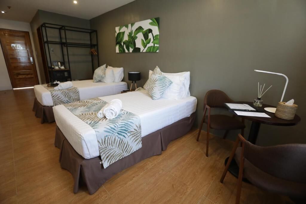Une chambre d’hôtel avec deux lits, un bureau avec une lampe et une chaise.