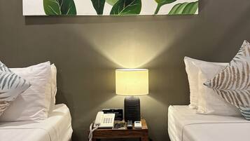 Een hotelkamer met twee bedden, een nachtkastje met een lamp, een telefoon en een bordje met een alarmtelefoon.