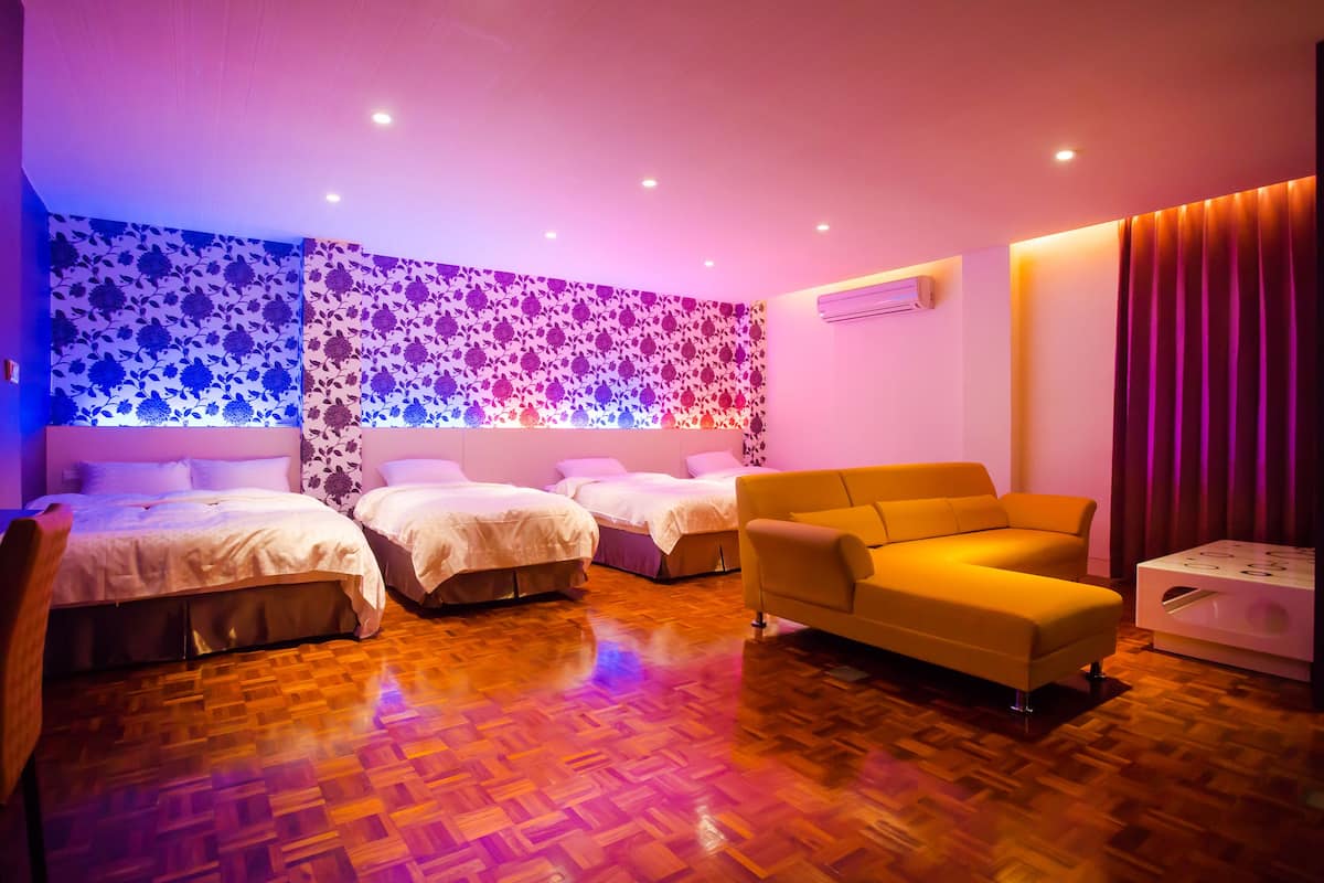 A hotel room with three beds, a sofa, and a small table.