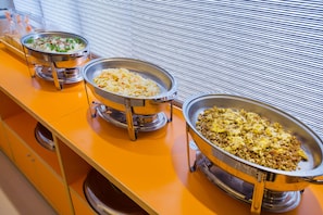 A buffet setup with three metal serving dishes on an orange countertop. - Yung An Business Hotel (Dounan)