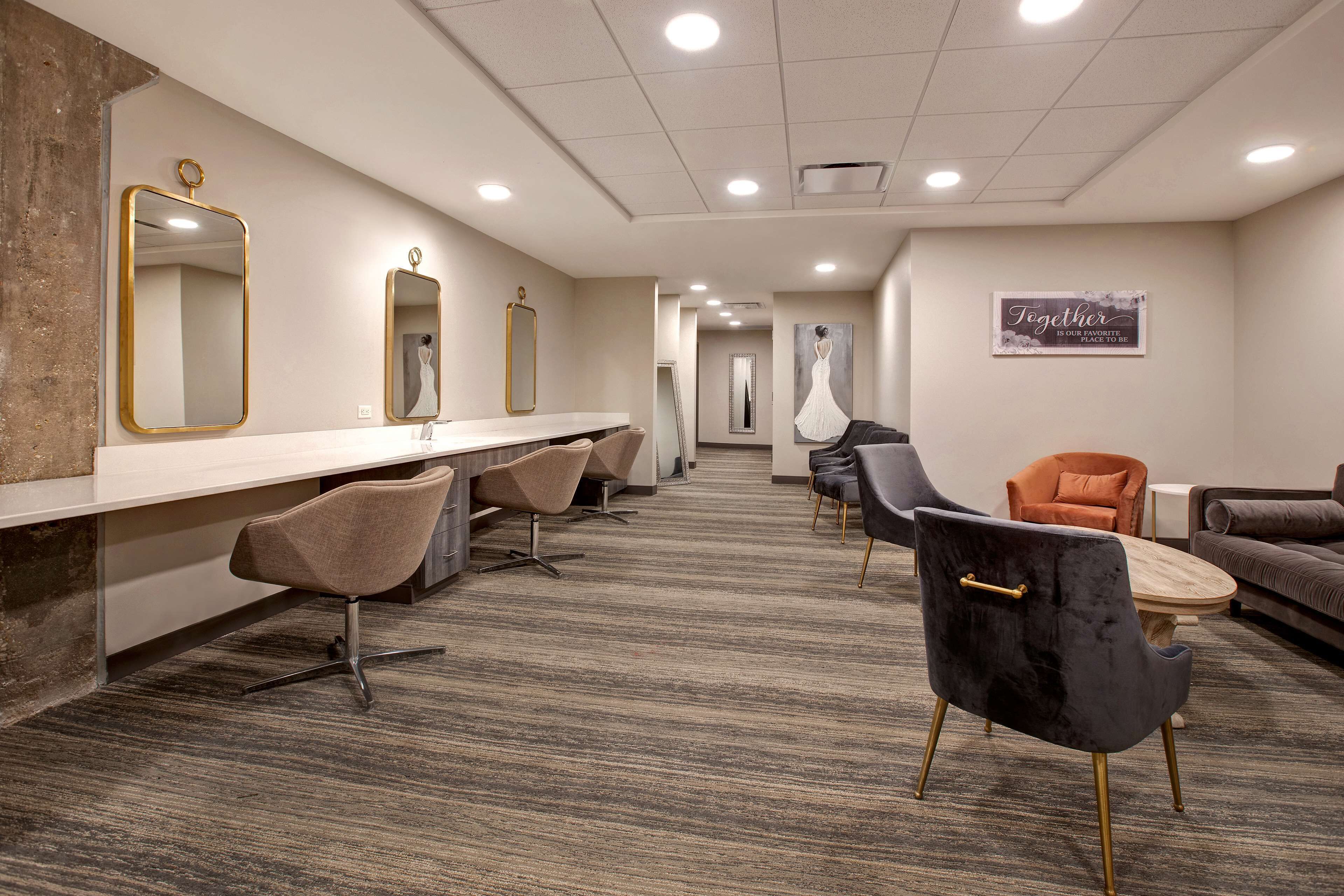 A hotel reception area with a long counter, multiple mirrors, and seating arrangements including chairs and sofas.