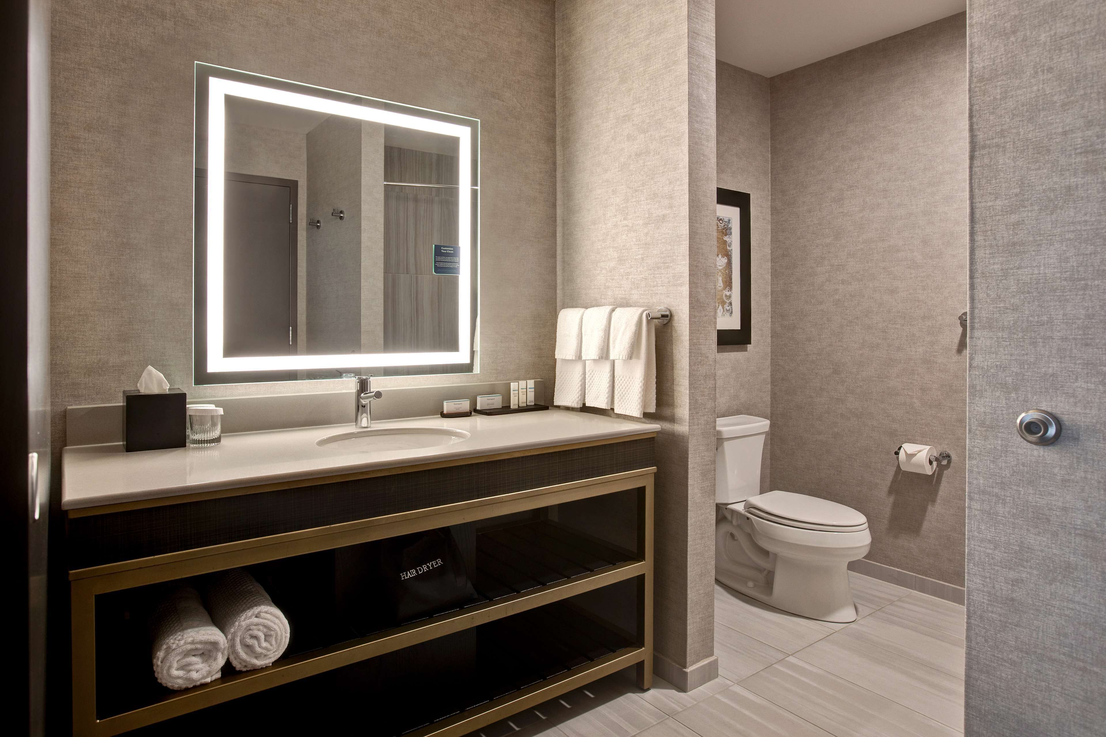 Une salle de bain moderne avec un grand miroir, un lavabo, des toilettes et un porte-serviettes.