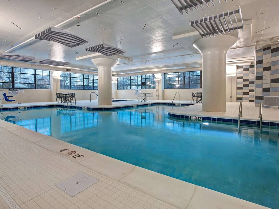 Una piscina interior con señalización clara, ventanas amplias y un revestimiento de azulejos.