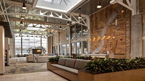 A spacious lobby with a high ceiling, large windows, and a reception desk. - Embassy Suites by Hilton Rockford Riverfront (Rockford)