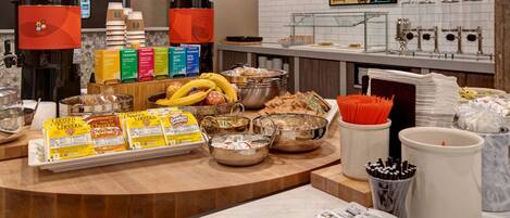 Un montaje tipo bufé con diferentes opciones de comida, como cereales, frutas y bebidas.