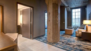 A hotel room with a large open space, a sofa, a coffee table, and a lamp. - Embassy Suites by Hilton Rockford Riverfront (Rockford)