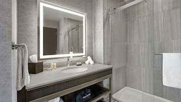 A modern bathroom with a large mirror, a sink, and a shower.
