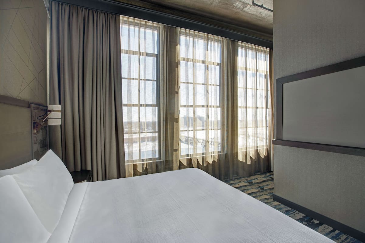 Habitación de hotel con una cama grande, un escritorio y una ventana con cortinas.