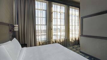 Een hotelkamer met een groot bed, een bureau en een raam met gordijnen.