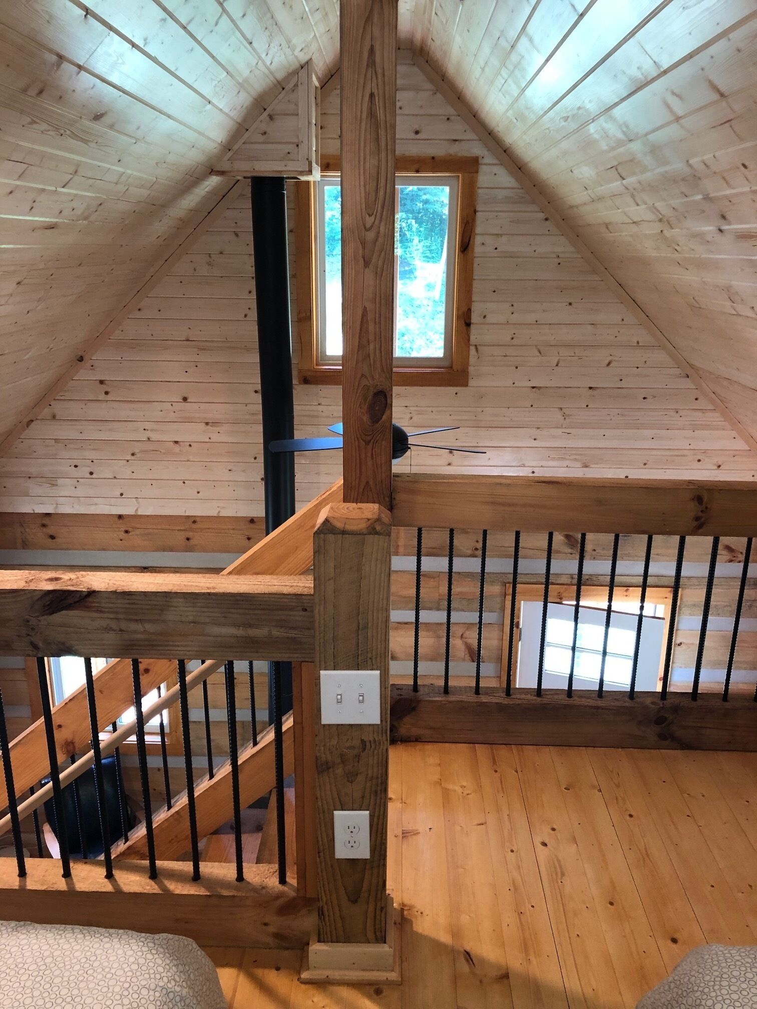Un intérieur en bois avec un plafond en pente, une fenêtre et un escalier.