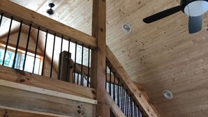 Interior de madera con escalera, ventilador de techo y puerta con una ilustración de un ciervo.