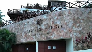 Edifício com fachada de pedra e o nome "PAJARO DE FUEGO" visível.