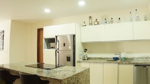 Uma cozinha moderna com bancadas de granito, eletrodomésticos de aço inoxidável e diversos frascos nos armários superiores.