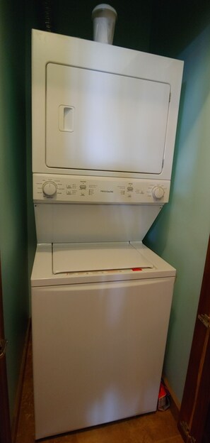 A front-loading washer and dryer unit with control panels and a vent pipe on top.