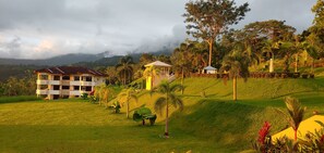 A hotel with multiple buildings, lush greenery, and a hilly landscape.