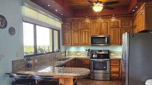 A kitchen with wooden cabinets, a stainless steel refrigerator, a microwave, and a granite countertop.