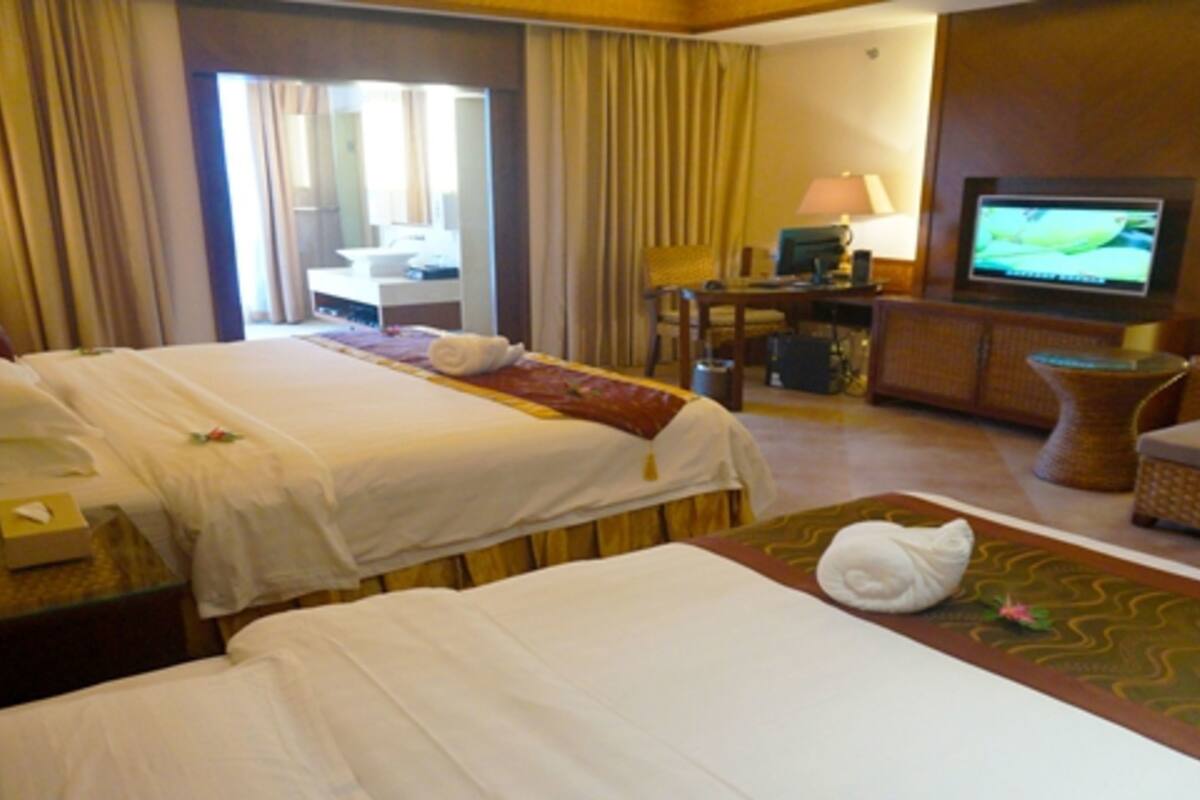 Habitación de hotel con dos camas, televisión, escritorio y una silla.