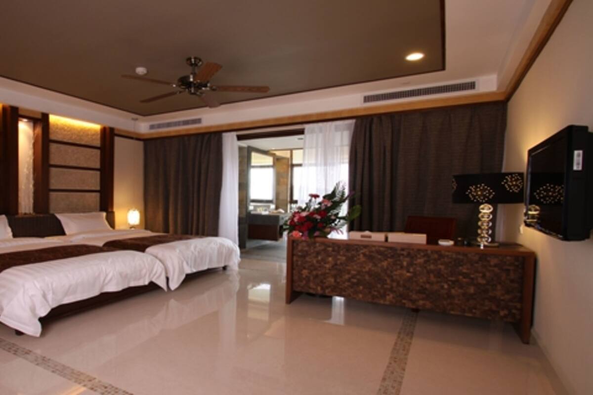 Una habitación de hotel moderna con una cama grande, un escritorio y un ventilador de techo.