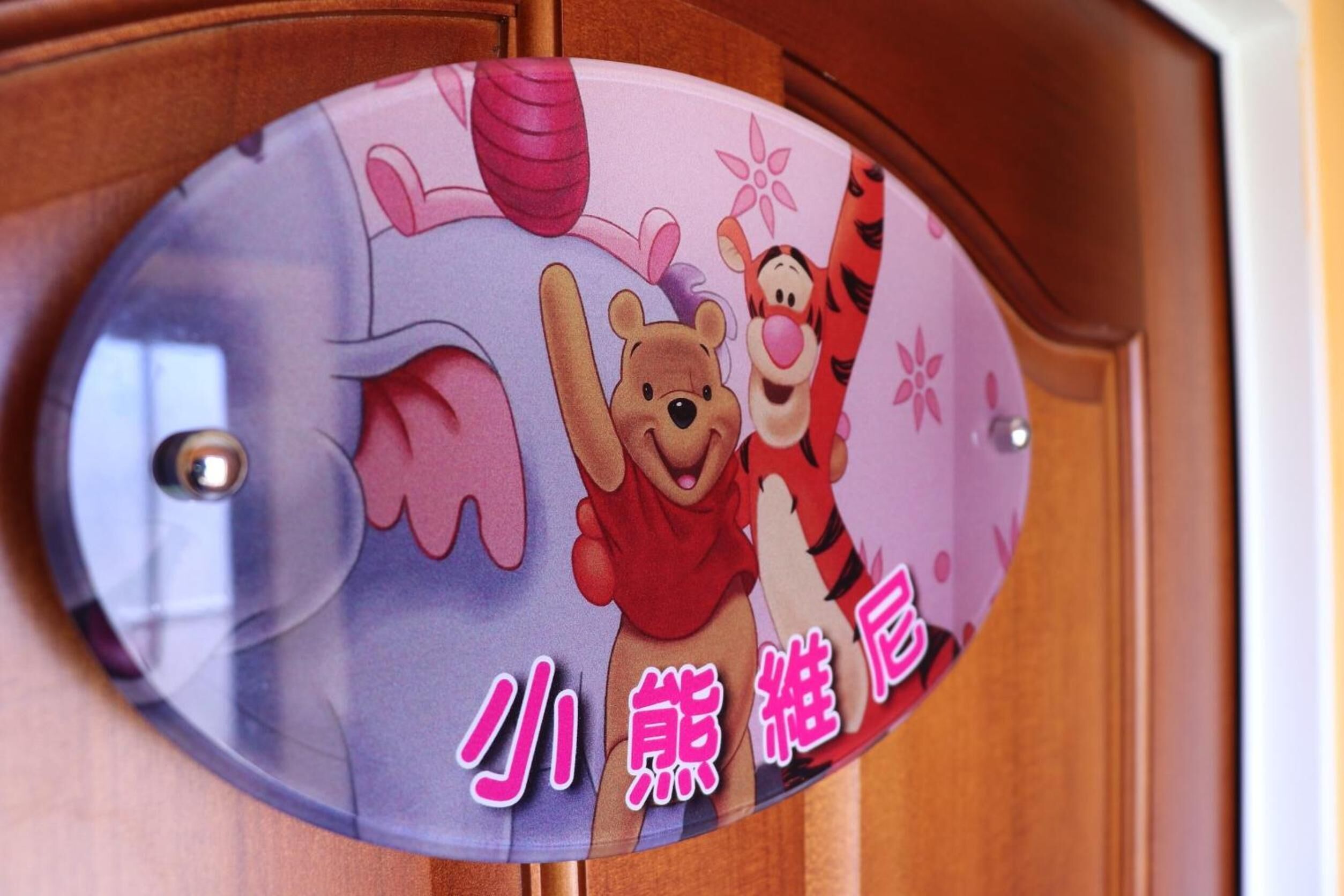 Une porte ornée d’une enseigne colorée représentant des personnages de dessins animés et du texte en chinois.