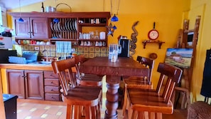A kitchen with wooden cabinets, a dining table with chairs, and a clock on the wall.