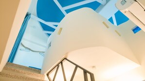 Un interior moderno con una escalera que conduce a un techo luminoso y de diseño geométrico.