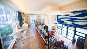 A spacious interior with a balcony, large windows, and a modern staircase. - Indigo Homestay (Magong)