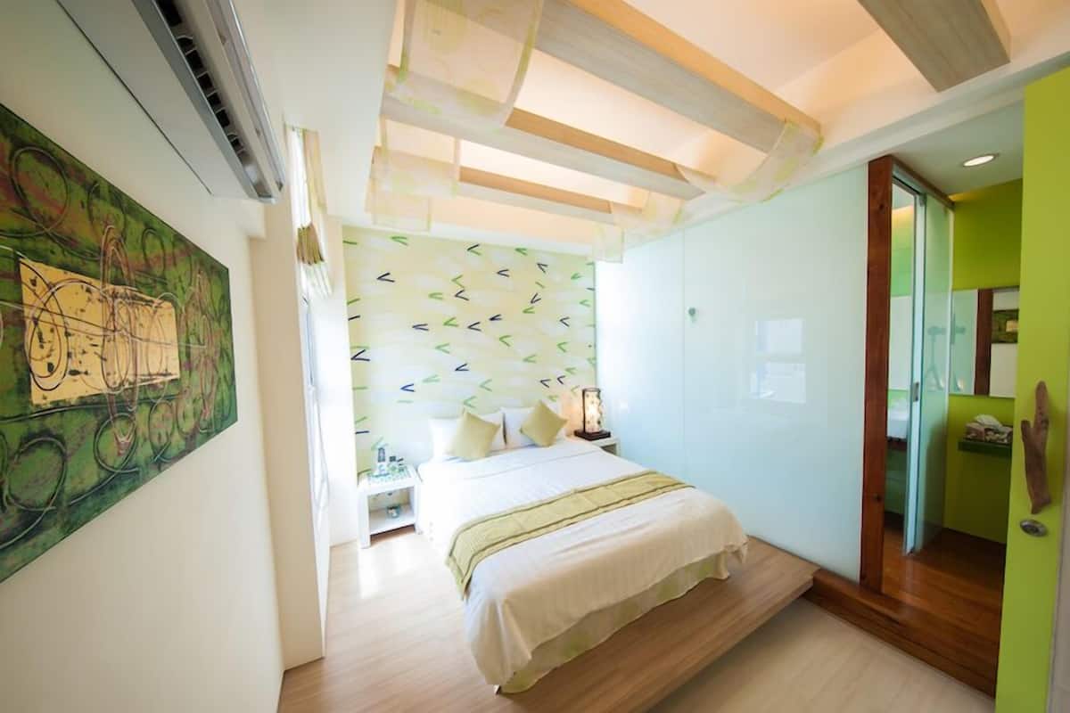 A modern bedroom with a bed, a nightstand, and a wall with abstract art.