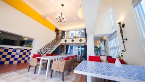 A spacious indoor area with a dining table, chairs, and a staircase leading to an upper level. - Indigo Homestay (Magong)