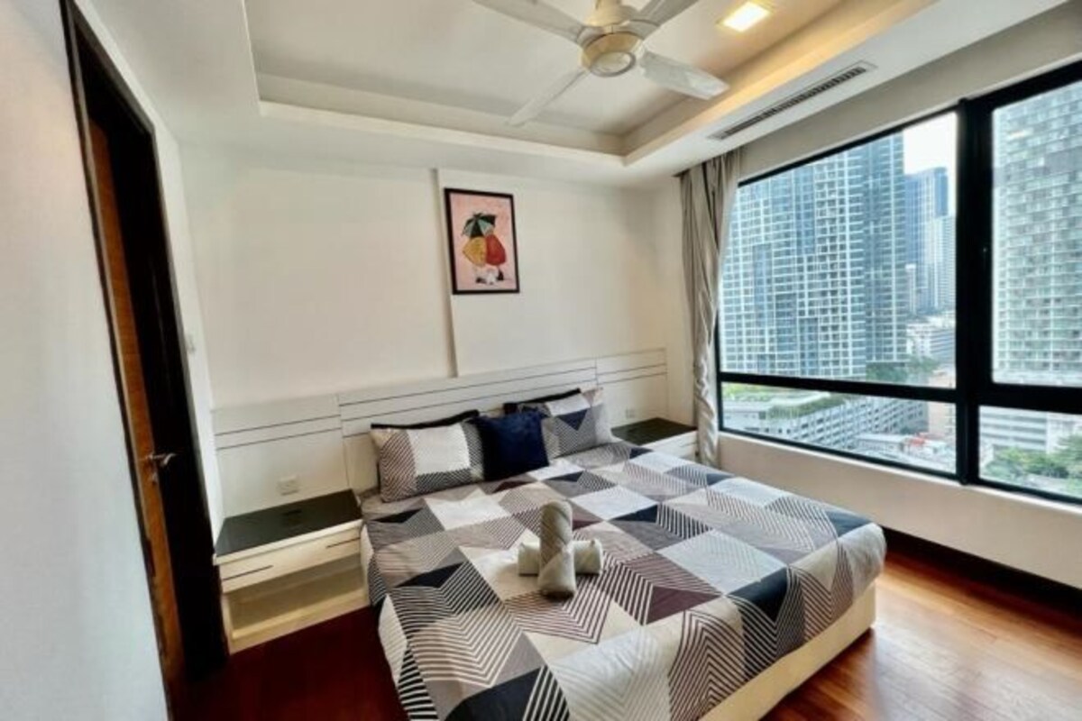 A modern bedroom with a large bed, a ceiling fan, a city view, and a framed picture on the wall.