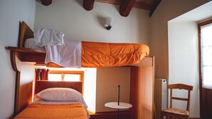 Une petite pièce comprenant un lit superposé, une petite table ronde et une chaise.