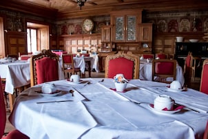 Un comedor con mesas dispuestas para el servicio, paneles de madera y un reloj en la pared.