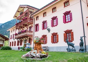 Un edificio tradicional con balcón, varias ventanas y estatuas exteriores.