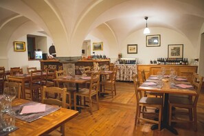 Ein Restaurant mit Holztischen und -stühlen, einer Bar und gerahmten Bildern an den Wänden.