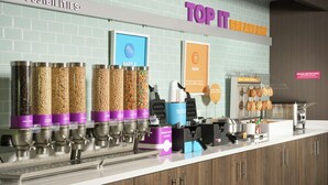 Un buffet pour le petit-déjeuner comprenant des gaufres, des distributeurs de sirop pour gaufres, un panneau indiquant les restrictions alimentaires et un présentoir à gaufres.