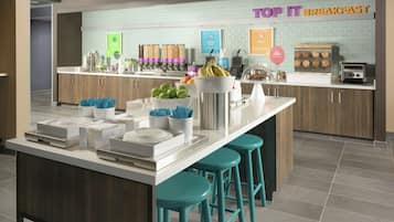 A modern breakfast bar with a sign reading "TOP IT BREAKFAST," featuring a variety of food items and a coffee station.