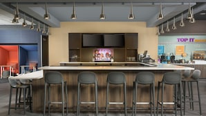 Un espace bar moderne doté d’un îlot central, de tabourets de bar et d’un éclairage suspendu.