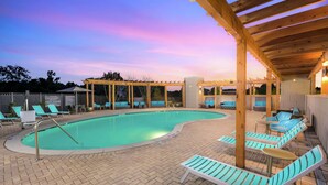 Un espace piscine avec des chaises longues et une pergola en bois.