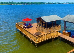 A wooden deck with a dining area, a small covered seating area, and a water view. - Château Jarreau on the false river (Oscar)